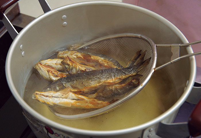 ［２］串魚を洗って戻したら、だしをとるために別の鍋で5分ほど煮て引き上げる。