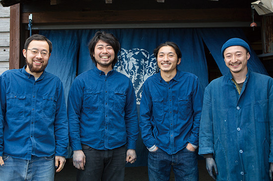 自らの手で染めた藍色の衣服を身にまとうBUAISOUのメンバー。左から三浦佑也さん、渡邉健太さん、楮覚郎さん、結城研さん。自分たちで牛舎を改造してつくった作業場 兼 オフィスの前で