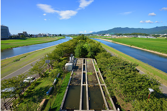 屋上から見た遠賀川（左）と彦山川。敷地内の〈春の小川〉は、浄化された水の流れだ。