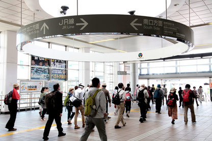 武蔵溝ノ口駅改札口天井の「久地円筒分水」モニュメントの下を歩く参加者たち