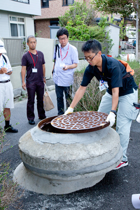 参加者に説明するため、マンホールの蓋を開ける藤倉一紘さん