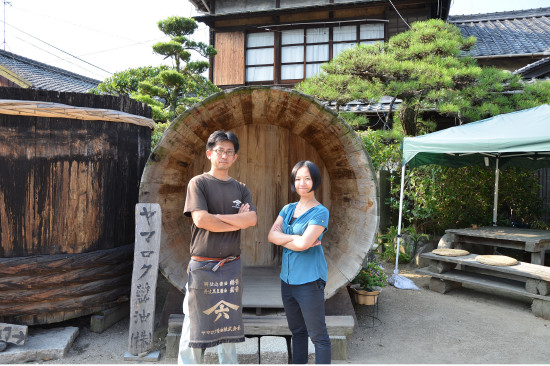 ヤマロク醤油株式会社の五代目・山本康夫さんと黒島さん。同社はステンレスやFRPのタンクを使わず、木桶61本だけで醤油をつくり続けている。敷地内の井戸から汲んだ水で仕込む。「ヤマロクさんは旨みの強いしっかりしたお醤油をつくられます」（黒島さん）