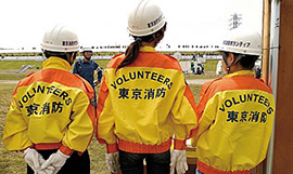 VOLUNTEERSとバックプリントされたジャンバー姿は、災害時支援ボランティアの女性たちである。