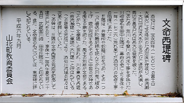 文命宮と並ぶ文命西堤碑。すぐ脇に川丈六地蔵の内の1体が〈山北岩流瀬のお地蔵さん〉として安置されている。