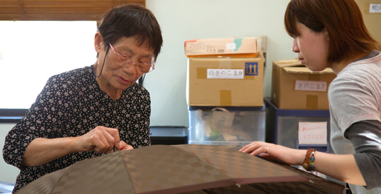 若い従業員に上ろくろの縫い方を指導する橋本さんの母親（左）。