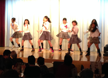 大広間のステージで歌って踊る「TKC48プロジェクト」のメンバー