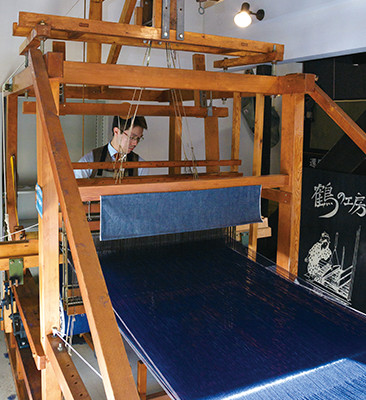 ここにしかない手織り機で「金丹」の生地を織る入社3年目の池田一貴さん
