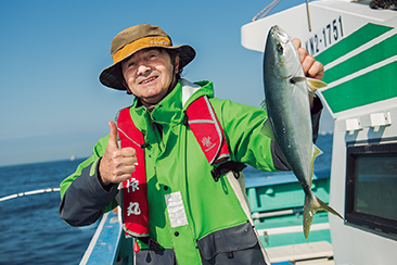 釣り上げたイナダ（ブリの幼魚）を手にするフランクルさん。