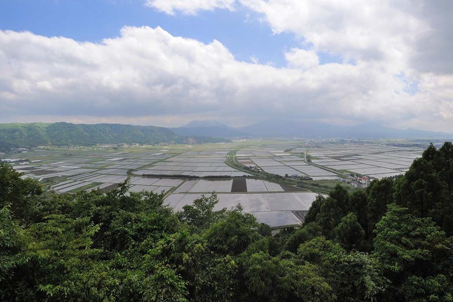 阿蘇北外輪の山麓から、満々と水をたたえた田んぼの風景を望む。