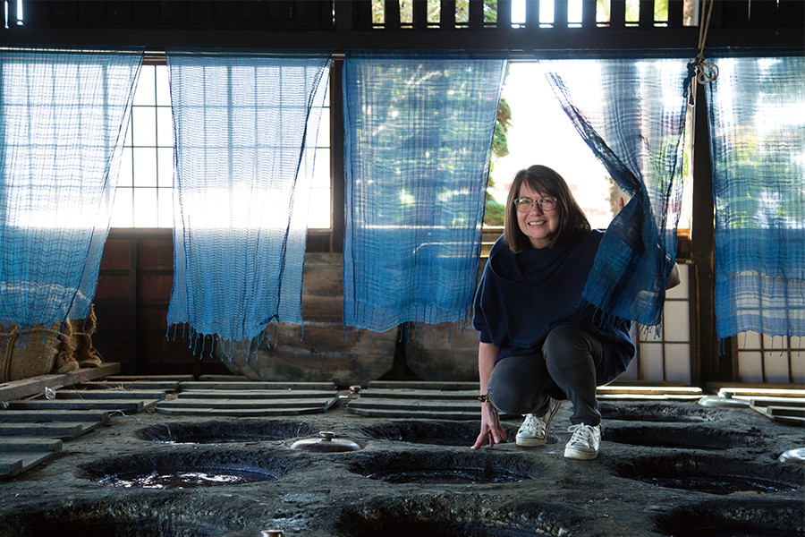 「日下田藍染工房」の染め場で微笑むリンダ・ブラシントンさん。作品づくりを通して得た、イギリスの合成藍と日本の天然染料による藍染めの違いを語った