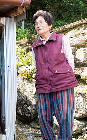 水上げ小屋について語る小谷卓子さんと小谷さん宅の水上げ小屋