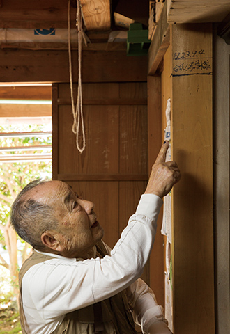 納屋に残る2011年の浸水跡を示す藤田瑳一さんと藤田さんの水上げ小屋