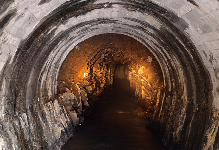 取水口から山を貫くトンネルの入口。少し奥に素掘りの跡が見える