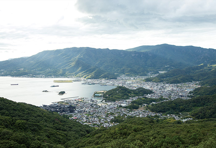 高台（碁石山）から見た「醤の郷（ひしおのさと）」と草壁港。しょうゆや佃煮をつくる工場が軒を連ね、歩くとしょうゆの香りが漂う。後背地にはしょうゆづくりに欠かせない水をもたらす山々がそびえる