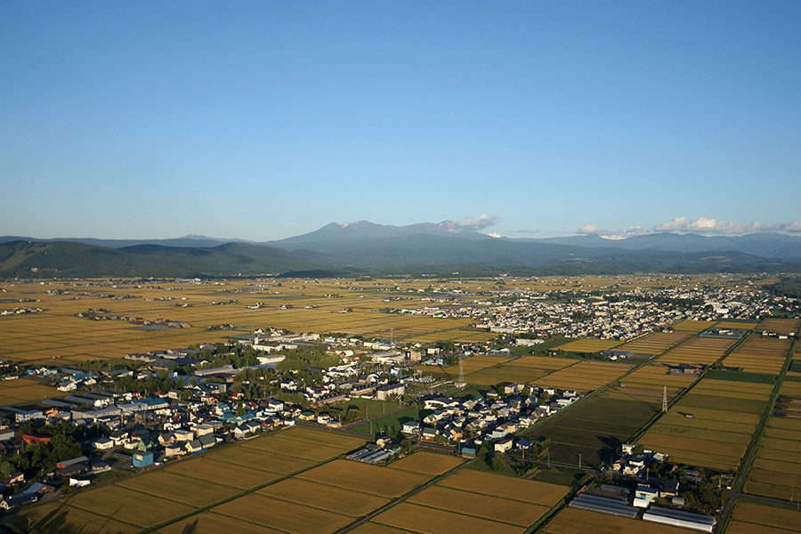 上空から見た東川町。遠くにそびえるのはこの地の象徴、大雪山連峰（提供：東川町）