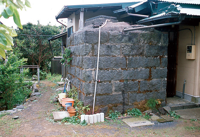 屋根に溜まった雨水を雨どいから貯水する三宅島の雨水貯留のしくみ。大きな石垣が貯水タンクとなっている。主に洗濯に使っているという 提供：須山聡さん