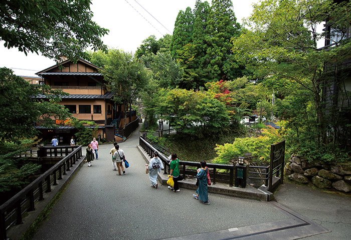 人が行き交う丸鈴橋。周囲の木々は山の雑木を移植したもの。言われなければわからないほど風景によくなじんでいる