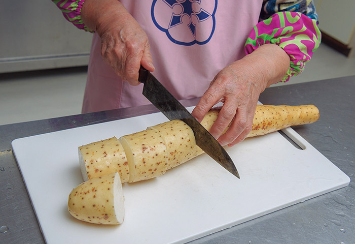 ［１］水をはった鍋を火にかけながら、材料を下ごしらえ。長芋はヒゲを火で焼き取り、皮付きのままぶつ切りに。昆布は水で戻し、切って結ぶ。ごぼう、油揚げは斜切りに。にんじんは飾り切りに。舞茸はサッとゆがいておく。下ごしらえが終わったら、硬いものから順に鍋へ。