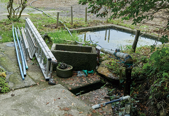 ライナープレートの排水口（手前）と、水を引き入れるために接続した農業用パイプ（奥）