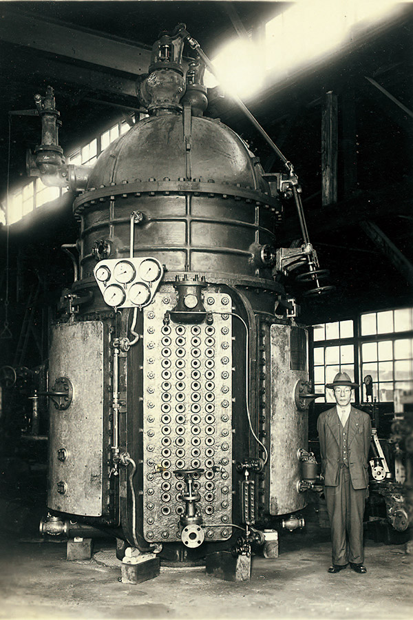 1950年代に株式会社ササクラが開発した蒸留式の船舶用造水装置。右に立っている人物（初代社長の笹倉敏郎氏）と比べるとその巨大さがわかる 提供：株式会社ササクラ