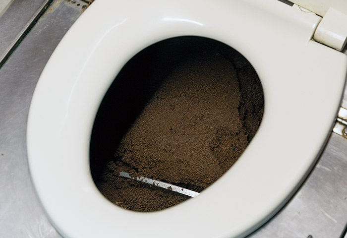 バイオトイレの内部。便器内のおがくずに潜む微生物が屎尿を分解する